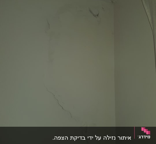 קיר עם סדקים ונזקי רטיבות בפינה